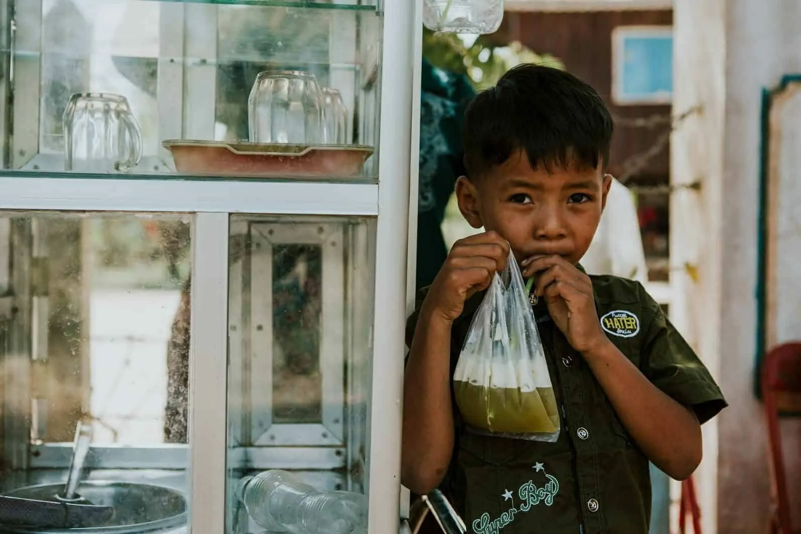 Young boy in the Children in Families Foster Care Program drinks a smoothie at a street stand
